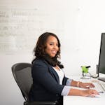 Woman in Professional Wear Seated in front of Monitor